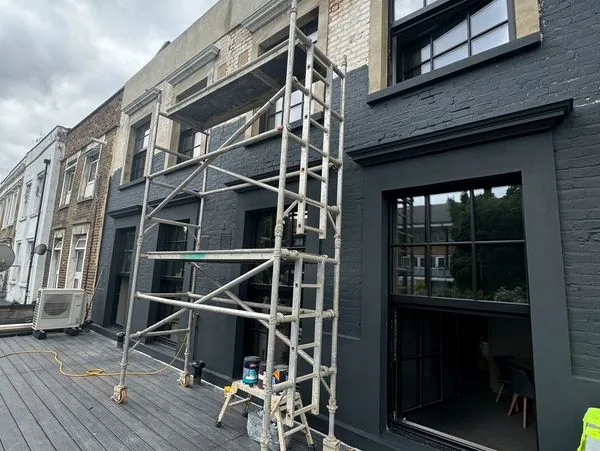 Rooftop scaffolding on charcoal black commercial building — facade refurbishment London